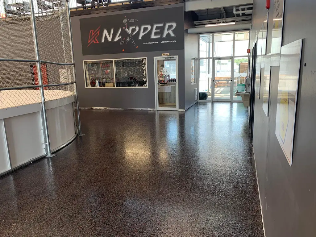 Intérieur du centre sportif Dek Saint-Roch avec un sol en époxy brillant, logo "K Nipper" sur le mur, et ambiance moderne et professionnelle.