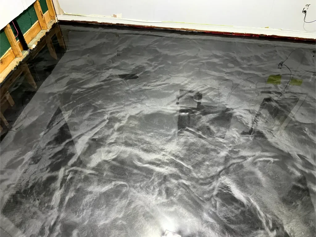 Epoxy flooring installation showcasing a glossy black finish with fluid patterns, emphasizing durability and high-quality material for residential spaces.