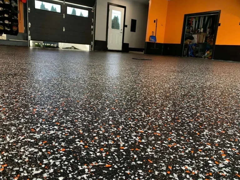 Epoxy garage floor with decorative black, white, and orange flakes, showcasing a durable and aesthetic finish in a residential setting.