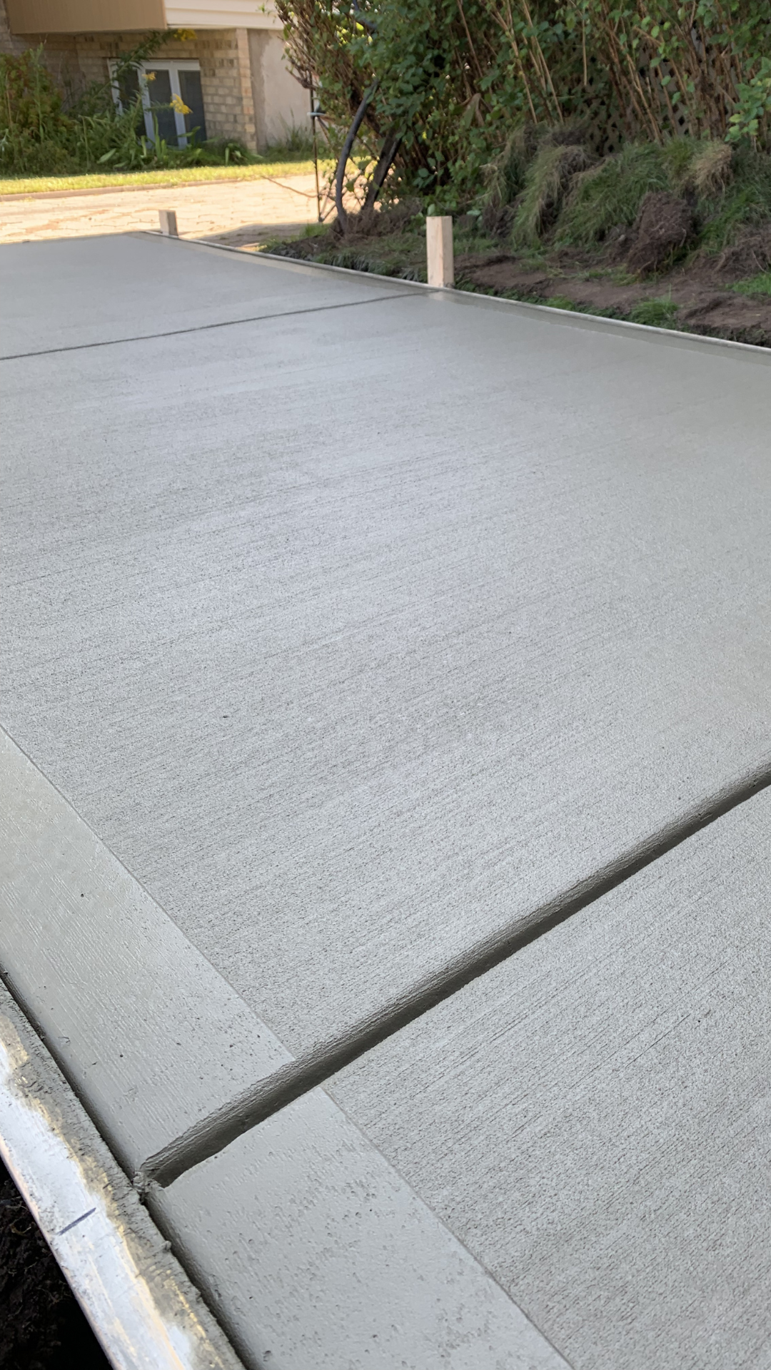 Freshly poured concrete slab with smooth finish, showcasing Bétonik's professional concrete repair services, surrounded by greenery and a residential setting.