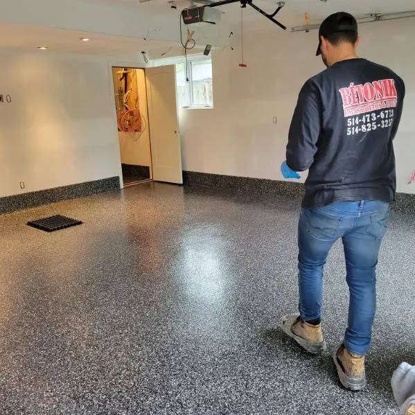 Homme en train de nettoyer un sol en époxy brillant, portant un vêtement de travail avec le logo de Bétonik, dans un espace intérieur bien éclairé.