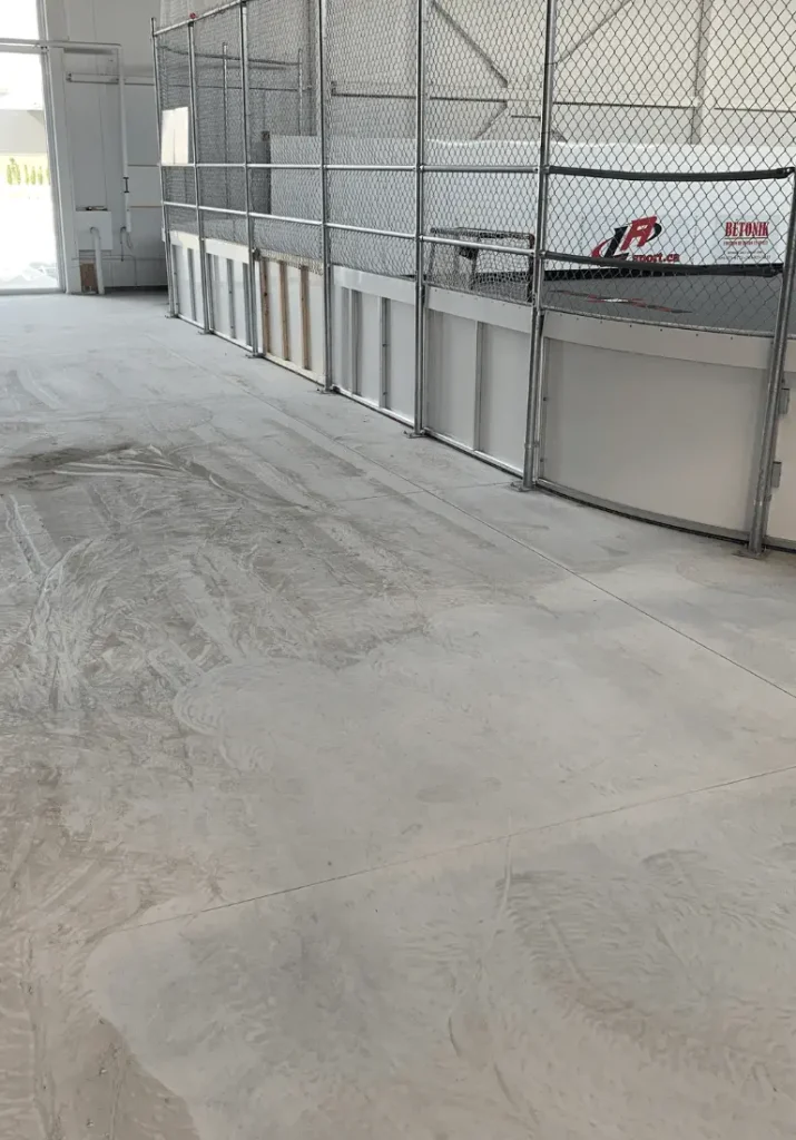 Surface de sol en béton époxy, espace rénové au centre sportif Dek Saint-Roch, avec clôture en filet, montrant l'achèvement de la transformation par Bétonik, mettant en valeur la facilité d'entretien et l'esthétique moderne.