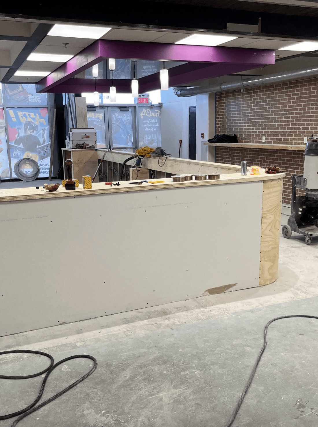 Construction of a commercial kitchen bar area with unfinished surfaces, visible tools, and materials, emphasizing the preparation for durable epoxy flooring installation.