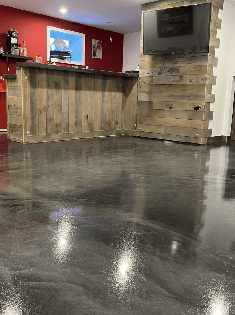 Seamless metallic epoxy flooring in a commercial space with a wooden bar and red wall, showcasing durability and professional appearance for restaurant settings.