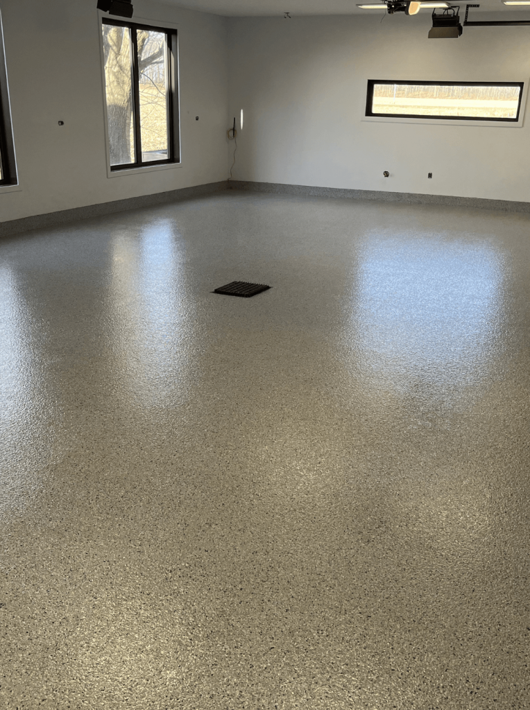 Epoxy garage floor with a smooth, glossy finish in a well-lit space, showcasing a clean and modern industrial aesthetic, ideal for durability and easy maintenance.