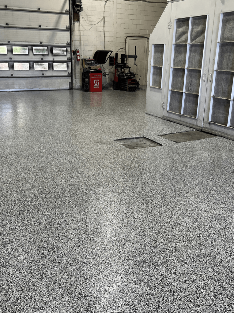 Epoxy garage floor featuring a modern granite look with vinyl chip blend, showcasing durability and a clean industrial aesthetic in a well-lit workspace.