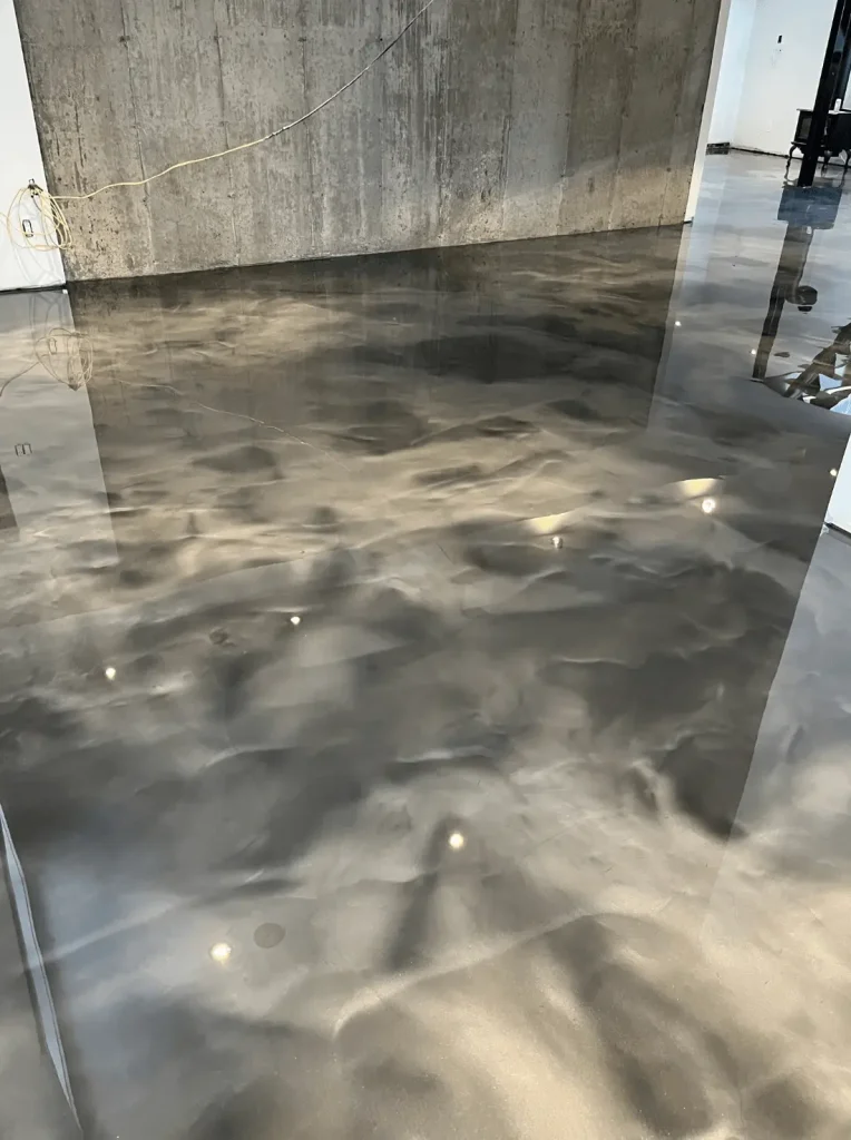 Epoxy flooring in a modern basement, showcasing a sleek slate gray finish with decorative reflective elements, enhancing aesthetic appeal and moisture protection.