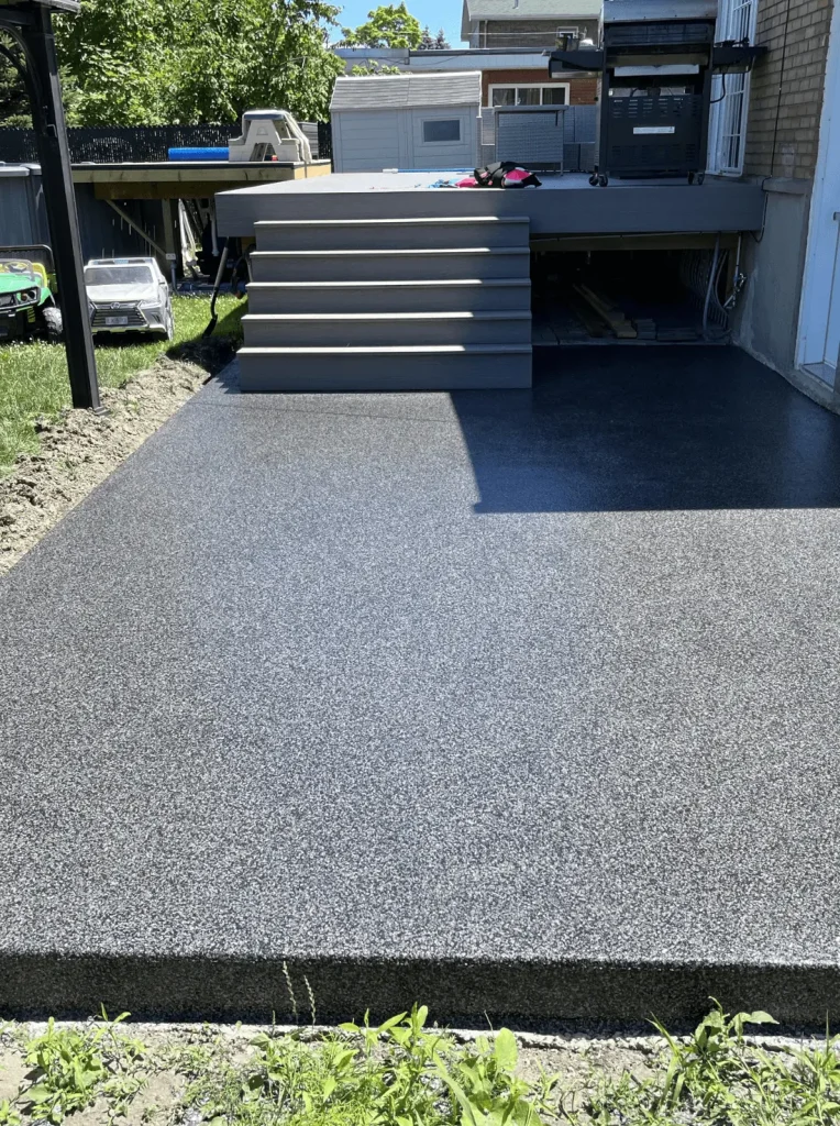 Concrete patio with steps, featuring a smooth surface, surrounded by grass and outdoor structures, illustrating concrete repair and reconstruction services.