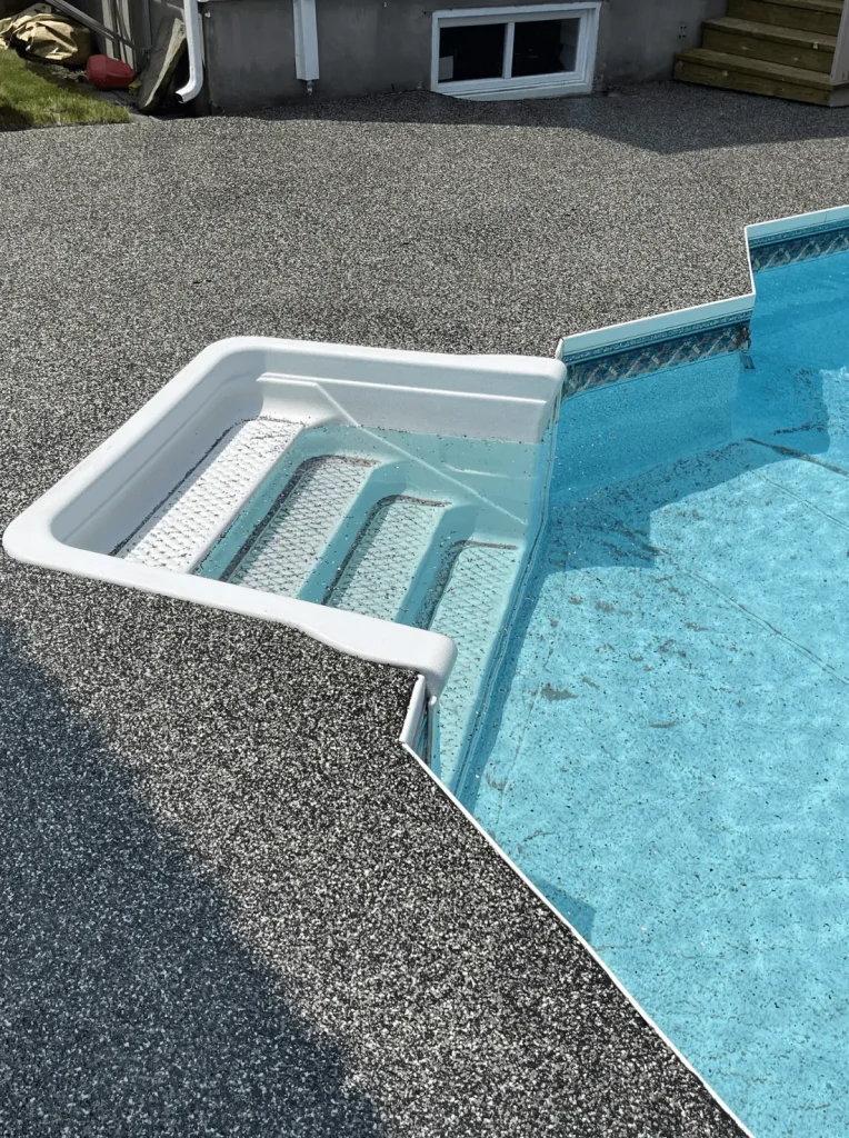 In-ground pool steps and surrounding concrete area, showcasing durable epoxy coating and repair work by Bétonik, emphasizing structural integrity and water resistance.