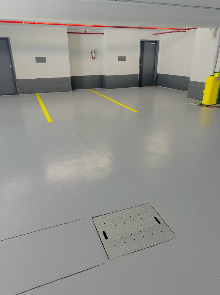 Sol intérieur de garage en béton époxy avec marquage au sol jaune, murs gris, et finition non glissante, illustrant la protection et durabilité des services de Bétonik à Saint-Hyacinthe.