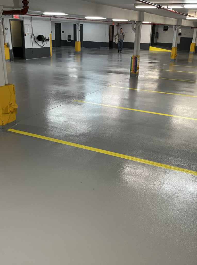 Garage floor with high-performance epoxy finish, yellow line markings, and clean, durable surface for enhanced safety and maintenance in a condo parking area.