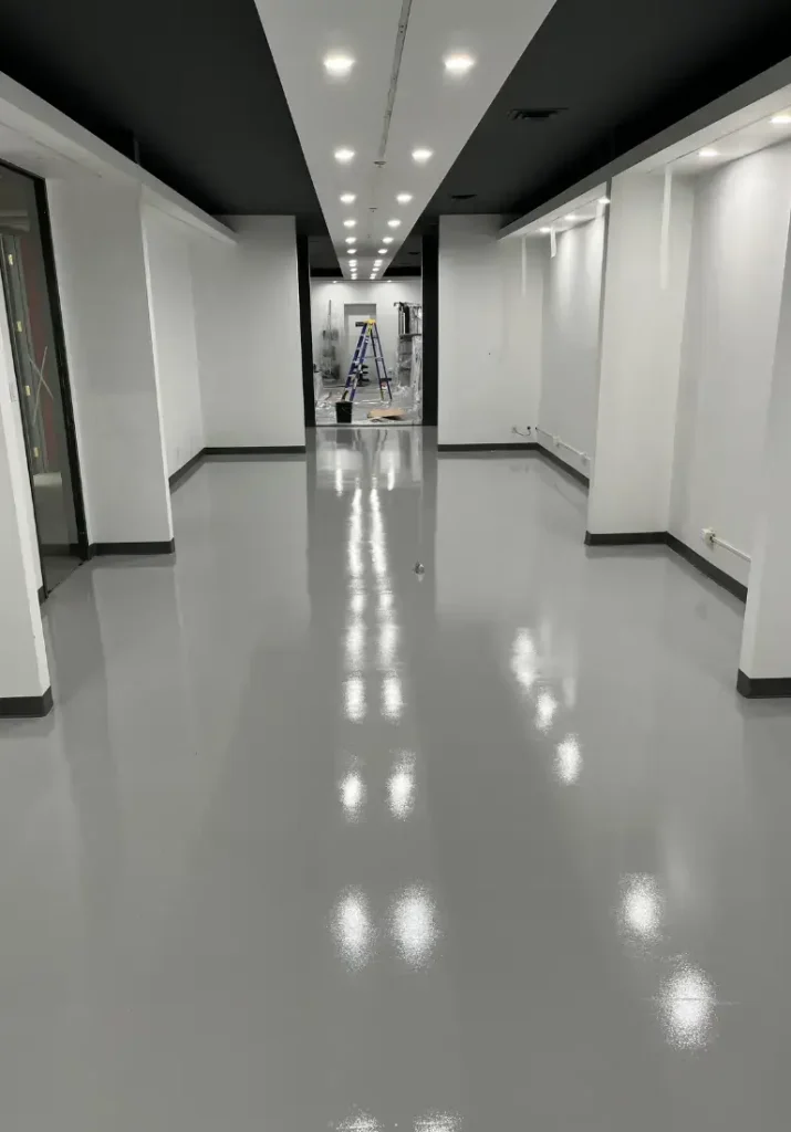 Intérieur d'une boutique avec un sol en époxy lisse et brillant, éclairage moderne, murs blancs et plafond noir, mettant en valeur l'esthétique et la durabilité des solutions de revêtement de Bétonik Inc.