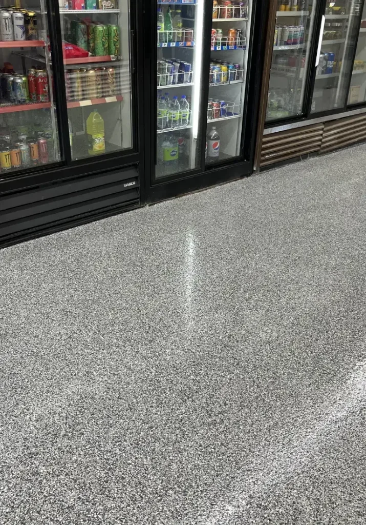 Surface en époxy floconneux et moderne, offrant une texture granitée, idéale pour les boutiques et les espaces commerciaux, mettant en valeur la durabilité et la facilité d'entretien.