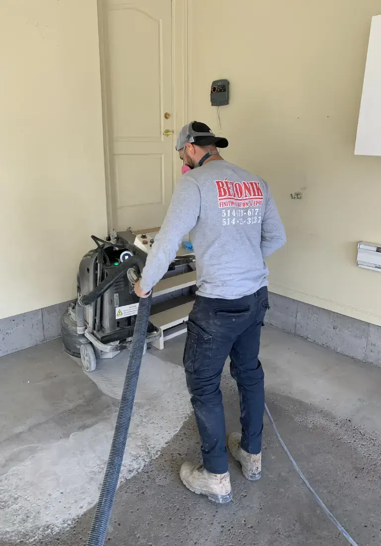 Technician operating diamond grinding equipment for epoxy flooring preparation in a commercial space, emphasizing Bétonik's professional installation services.