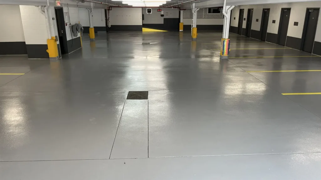 Indoor parking garage with a gray epoxy floor and stall markings, Greater Montreal