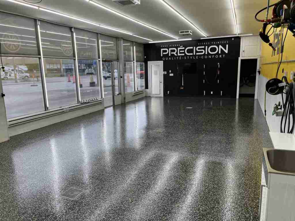 Dark flake epoxy floor in an auto shop, installed by B&eacute;tonik